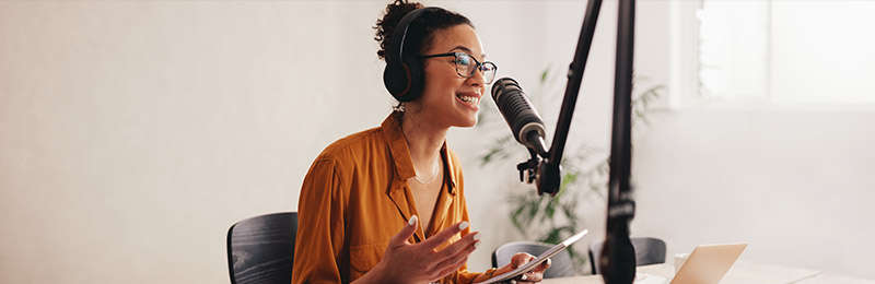 Female entrepreneur sitting at her desk with headphones on. Working on recording her sales strategy.