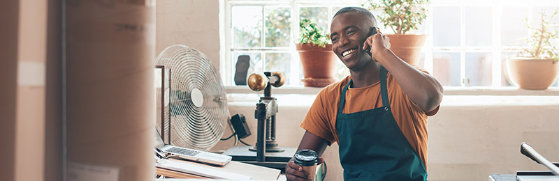 Male entrepreneur sitting at a desk in a home office. Chatting on the phone about his business and trying to fine tune his message for specific people.