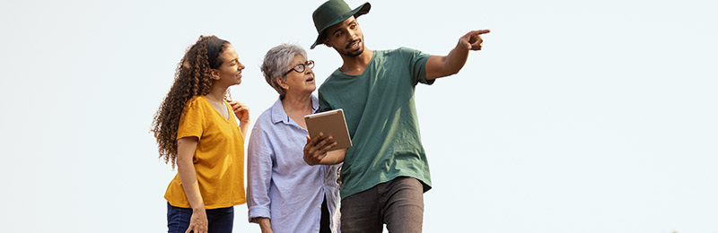 Male entrepreneur standing with two women pointing out ways that his service can benefit them.