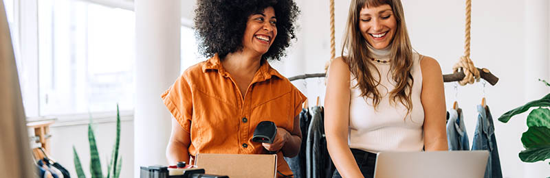 Female entrepreneur sharing her crowdfunding campaign with a friend by showing her laptop.