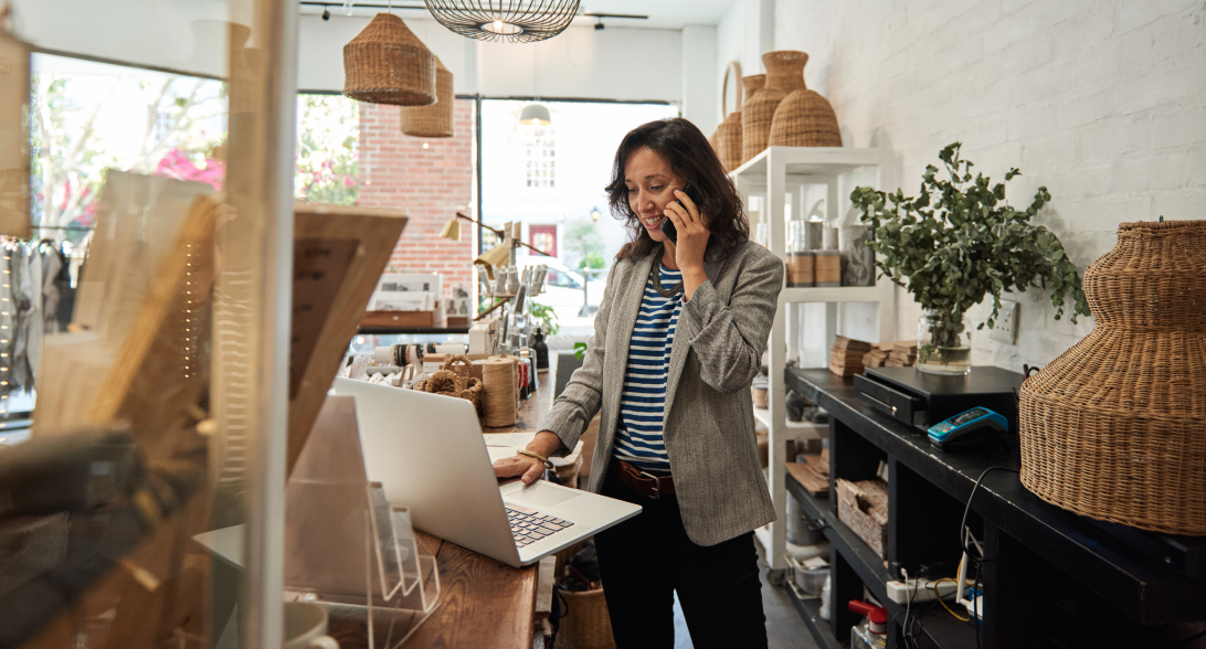 Woman working on laptop while on phone